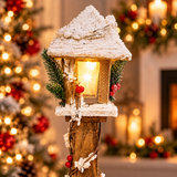 Close-up of the snowy wooden Christmas lamppost lantern with warm white LED glow, pine and red berries