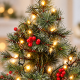 Close-up of frosted branches, red berries and warm white LEDs on mini Christmas tree
