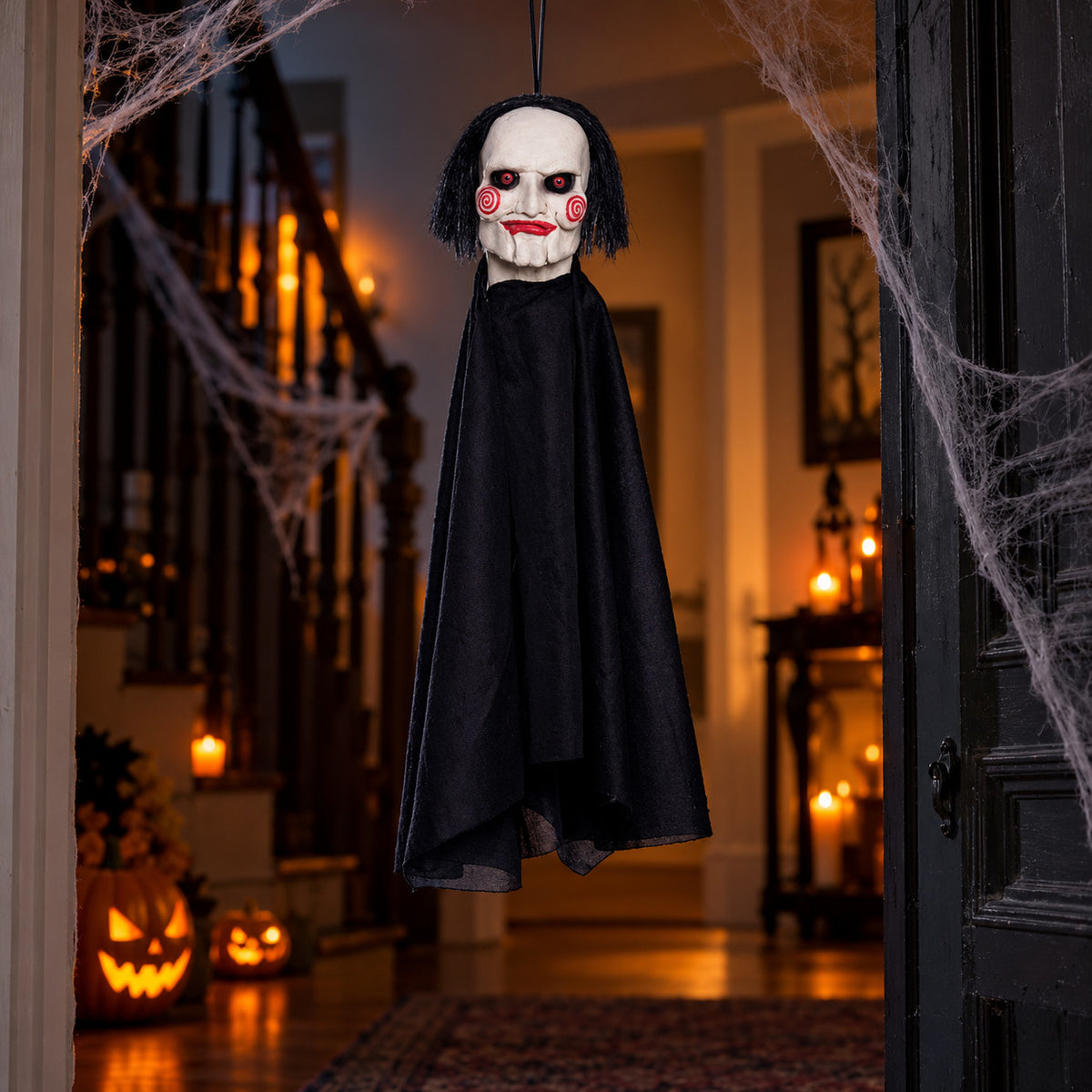Jigsaw Billy puppet Halloween hanging decoration displayed in a spooky doorway with cobwebs and pumpkins
