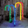 Four vibrant cloloured candy cane led stake path lights illuminated against a snowy backdrop, creating a festive and cheerful winter scene.
