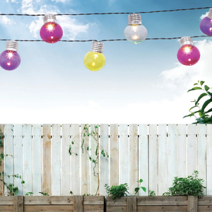 A string of amber lights hanging outdoors with a light bulb in focus against a blurry background.