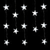 A close-up view of white star-shaped LED curtain string lights glowing softly against a dark background, creating a warm ambiance.