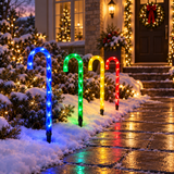 Four multicoloured LED candy cane stake lights lining a snowy pathway