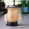 A gold and white mosaic glass wax melt warmer containing a light bulb, creating a warm and inviting ambiance.